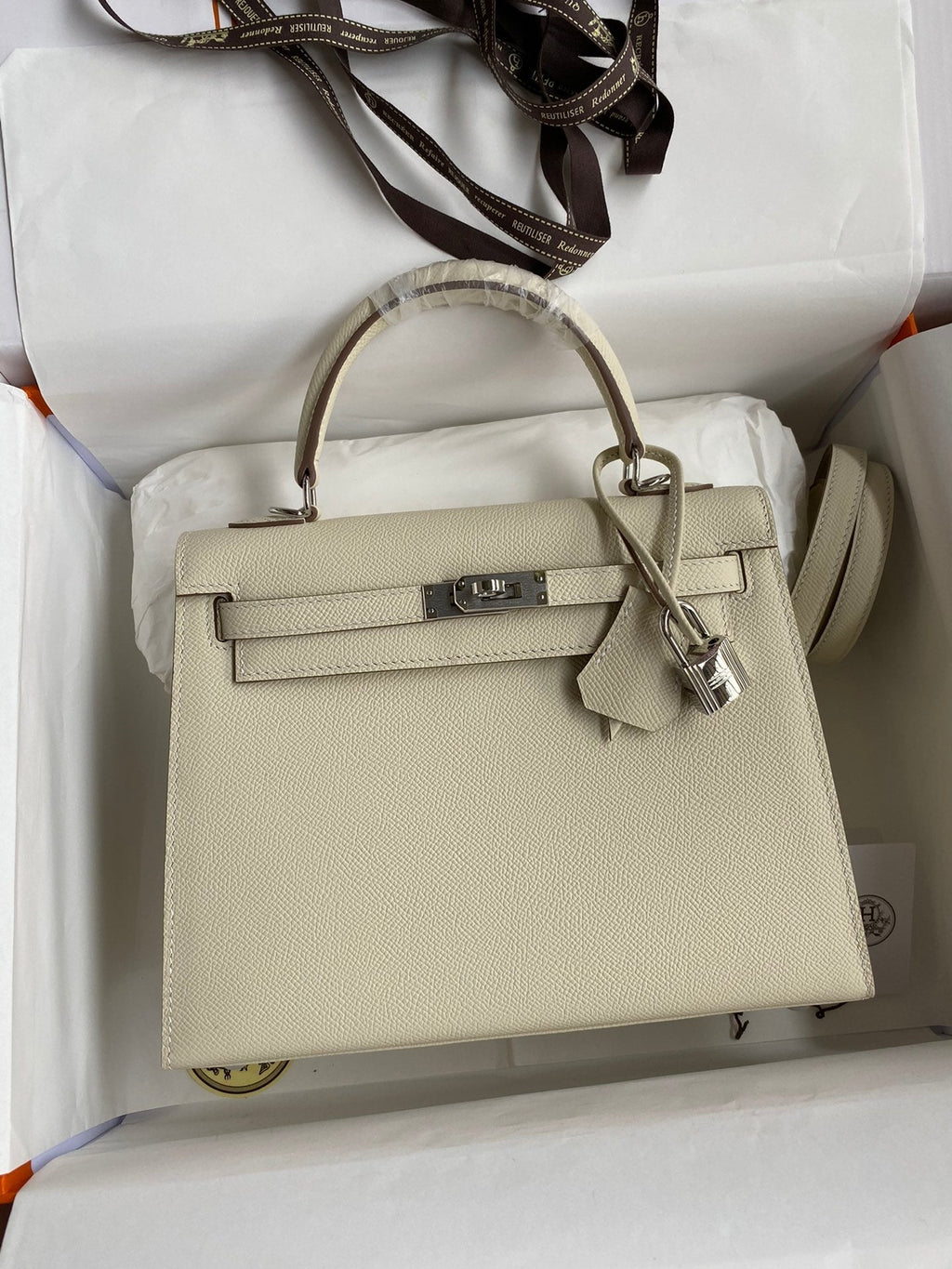 Beige handbag with gold hardware on a white background
