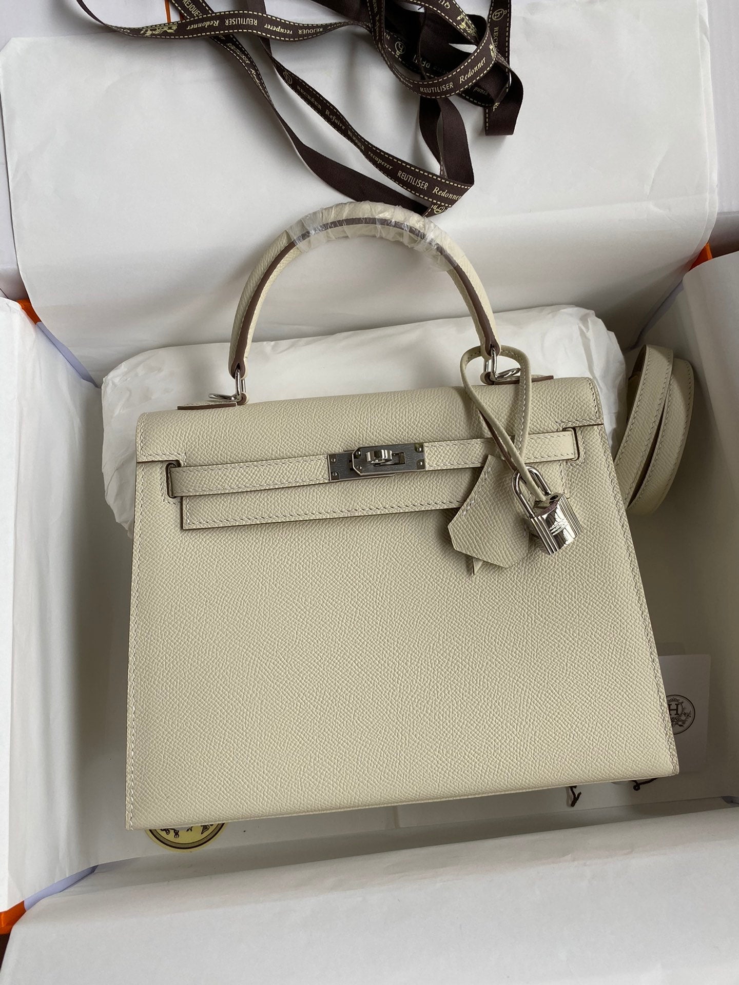 Beige handbag with gold hardware on a white background