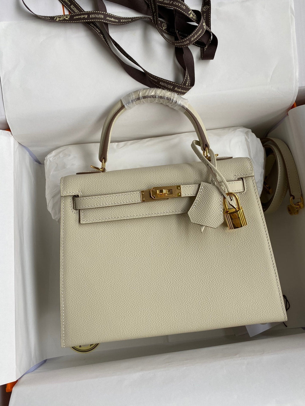 Beige handbag with gold hardware on a white background