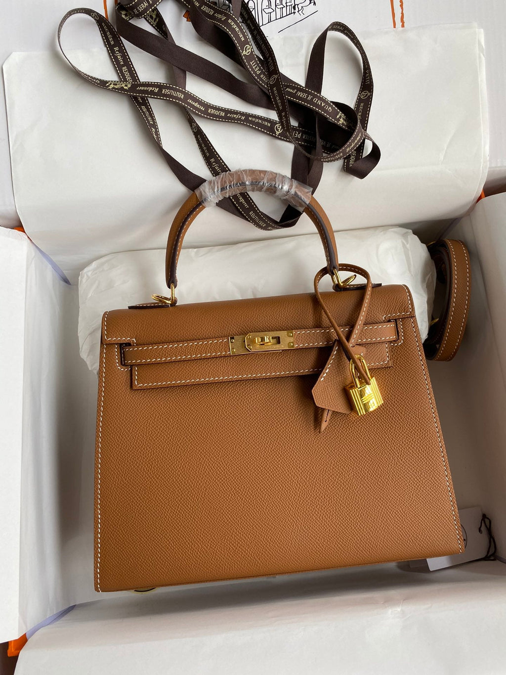 Brown handbag with gold lock on a white surface