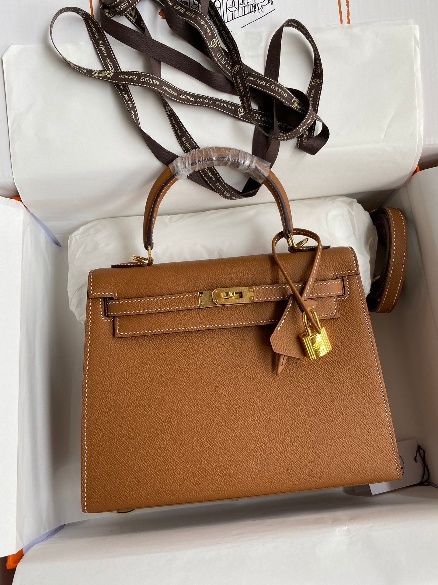 Brown handbag with gold lock on a white surface