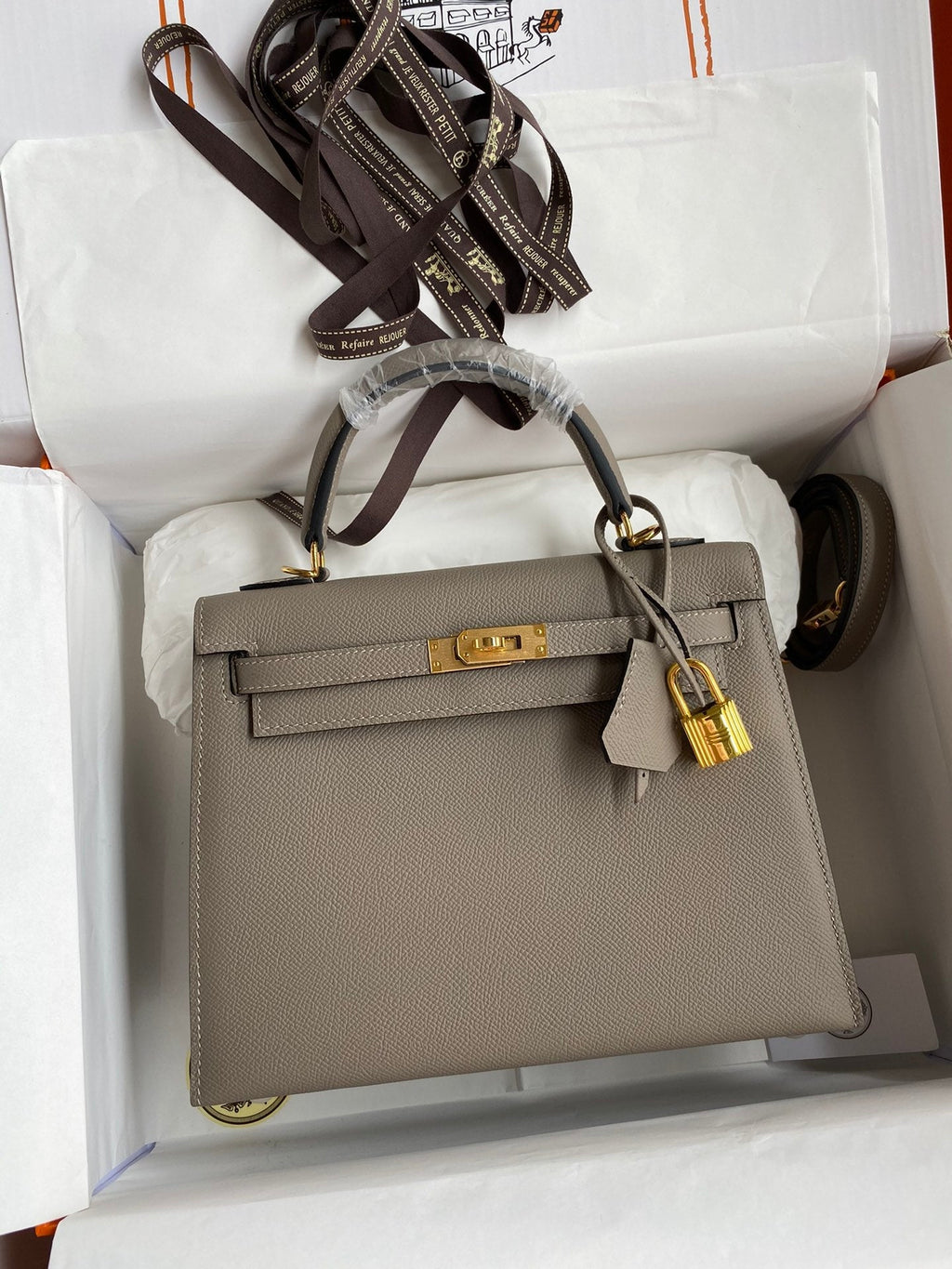 Gray handbag with gold hardware in a white box