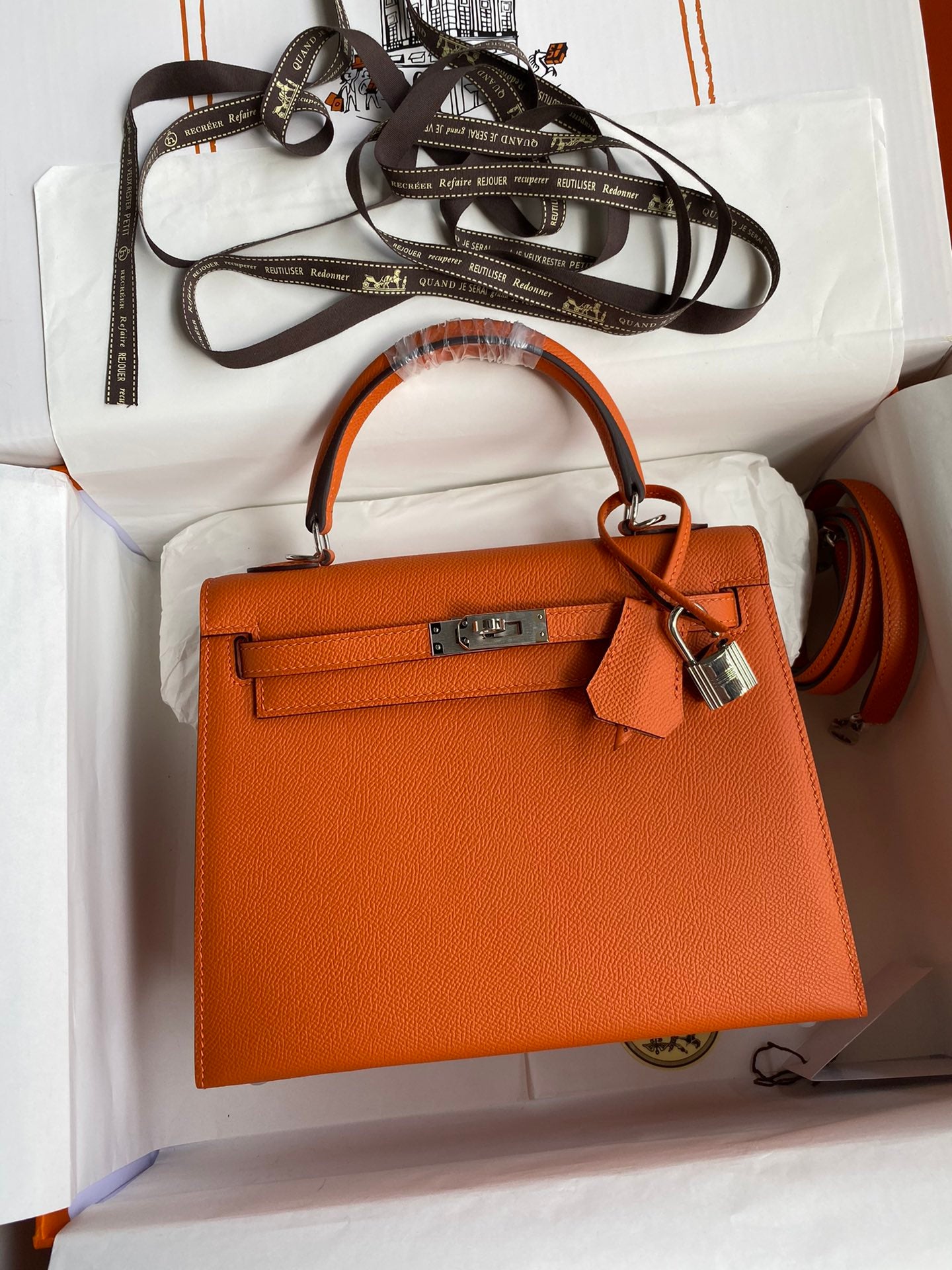 Orange handbag with matching strap on a white background