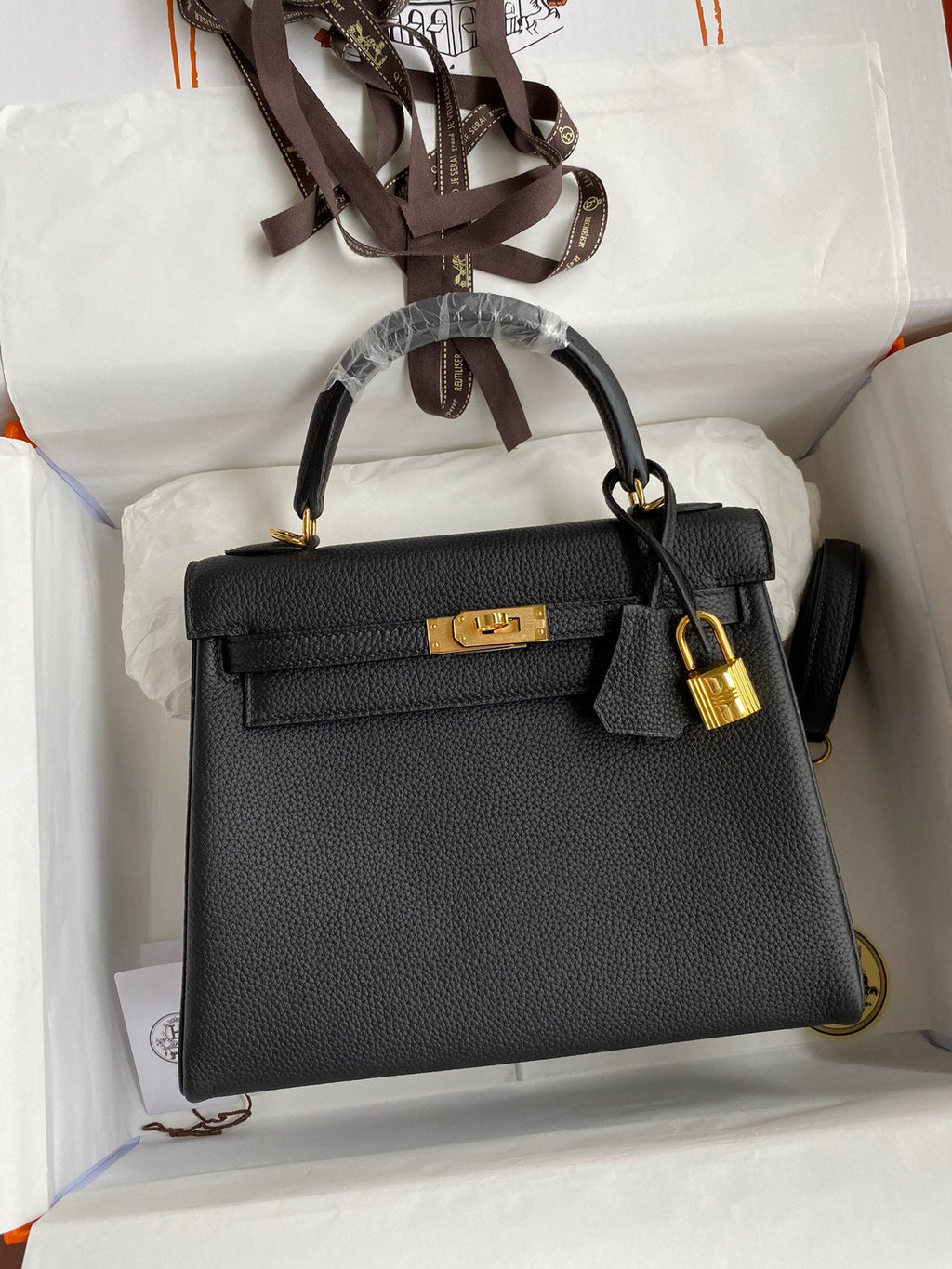 Black handbag with gold hardware in a white box