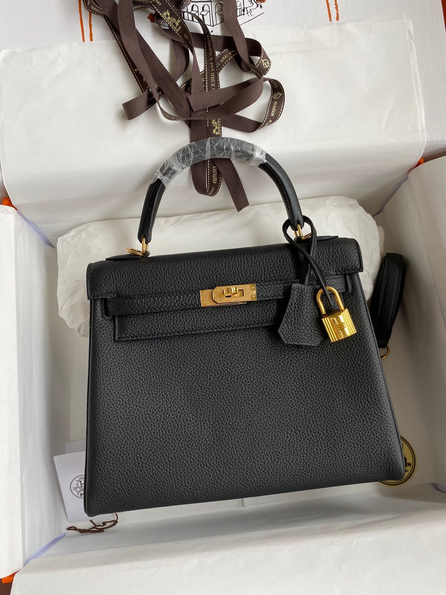 Black handbag with gold hardware in a white box