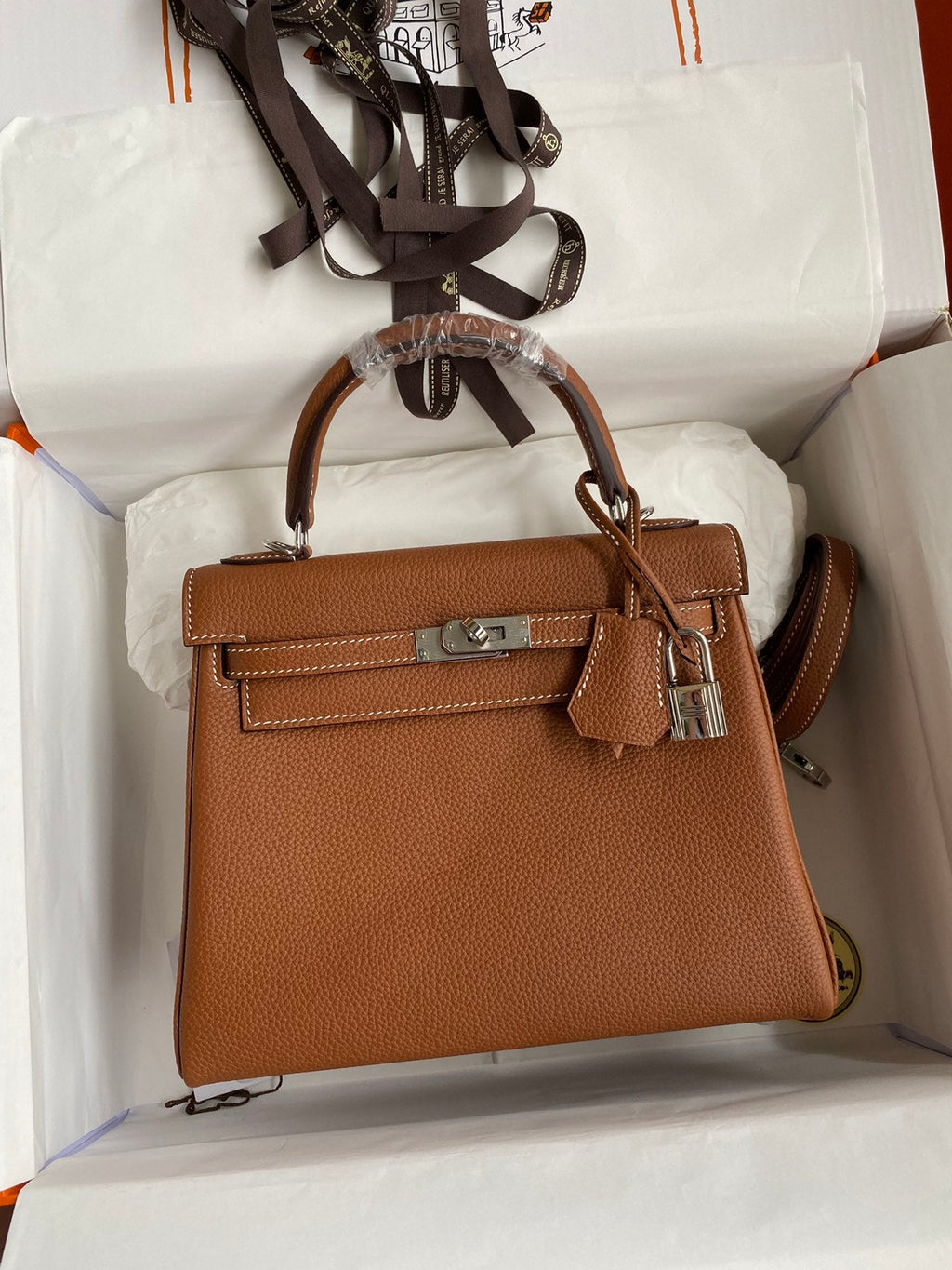 Brown handbag with a silver clasp on a white background