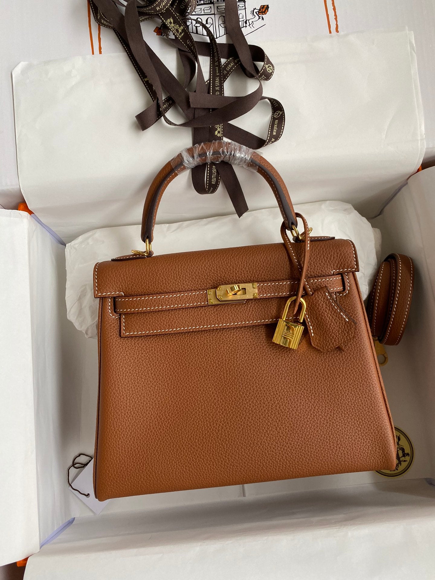 Brown handbag with gold hardware in a white box