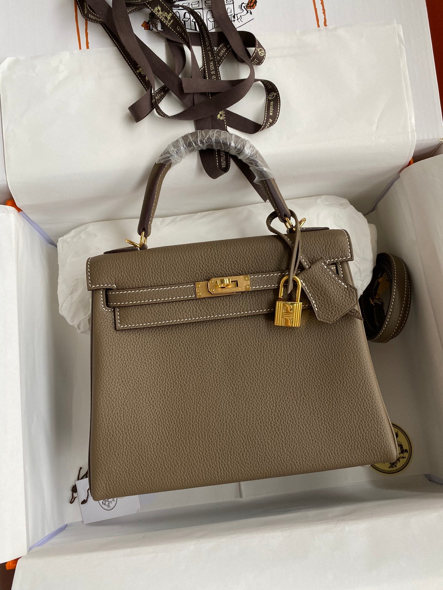 Brown handbag with gold hardware in a white box