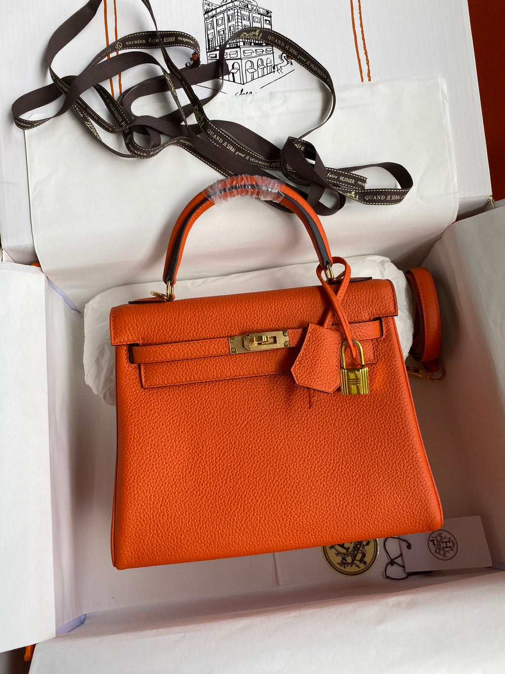 Orange handbag with gold hardware in a white box