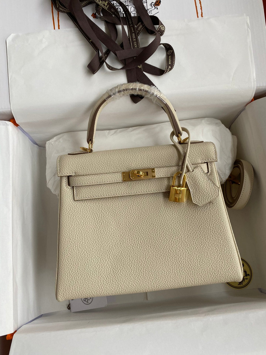Beige handbag with gold hardware on a white background