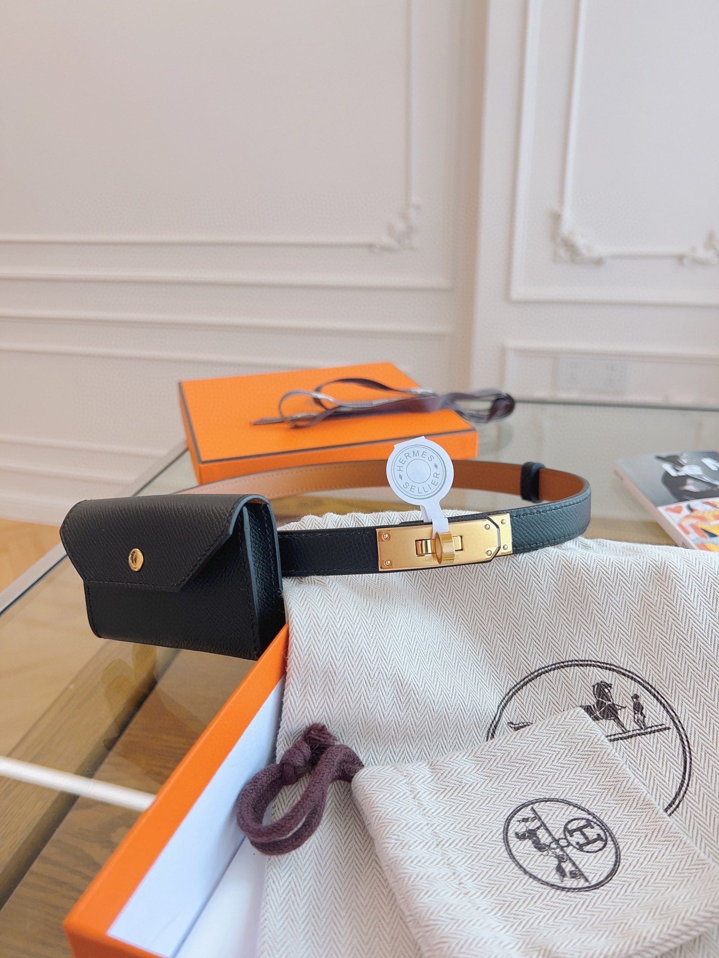 Bracelet with gold clasp, black pouch, and branded pouch on a wooden surface.