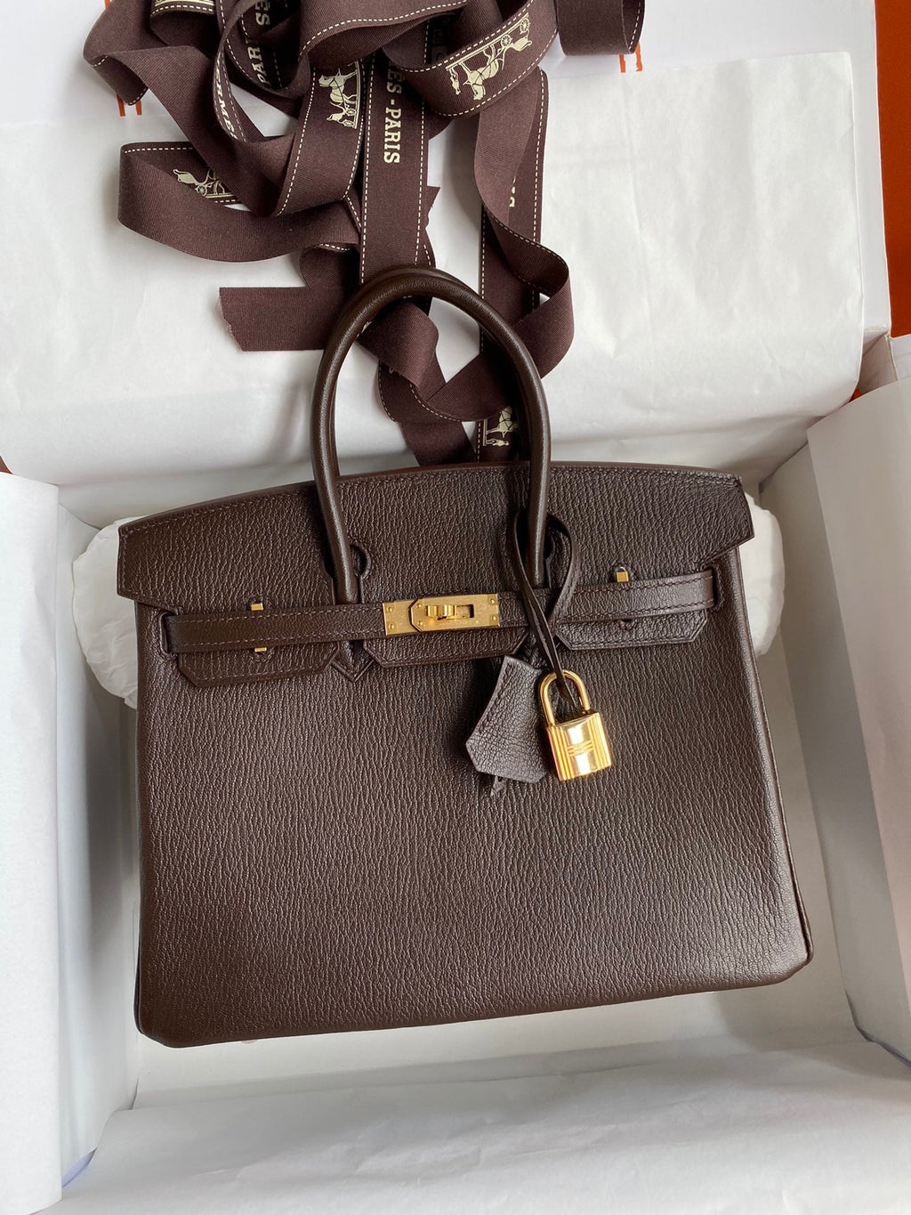 Brown handbag with gold lock in a box
