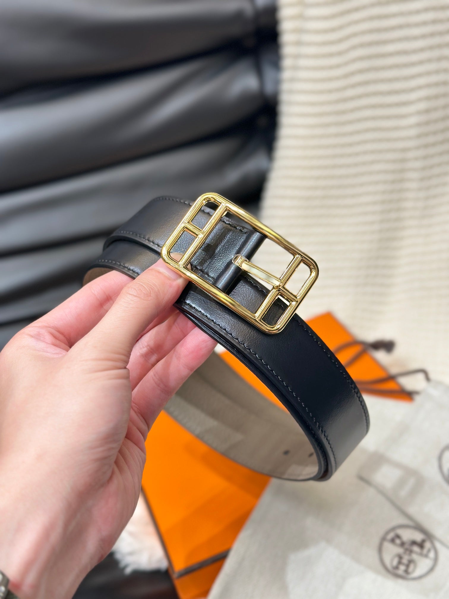 Black belt with a gold buckle held by a hand, with a blurred background