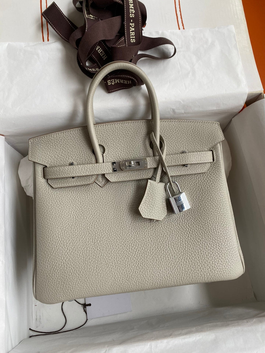 Beige handbag with a lock on a white surface