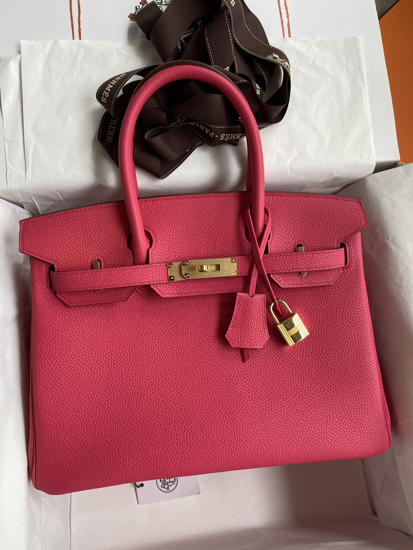Pink handbag with gold hardware on a white surface