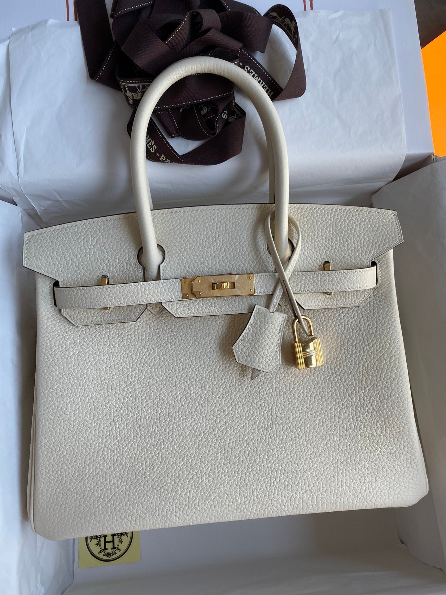 Beige handbag with gold hardware on a white background