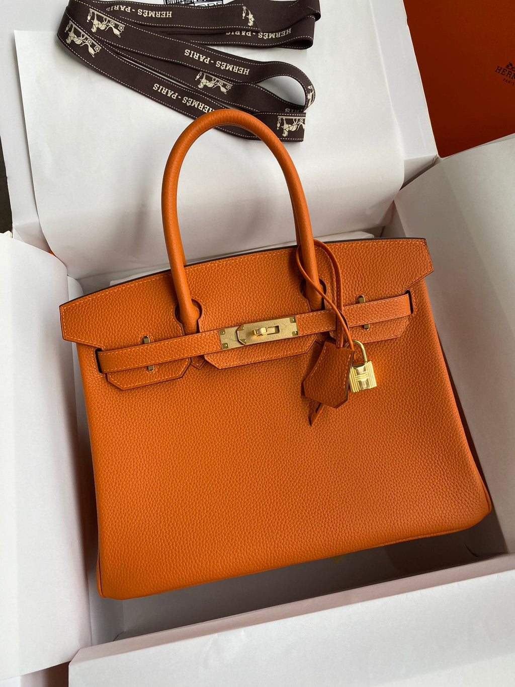 Orange handbag with gold hardware in a box