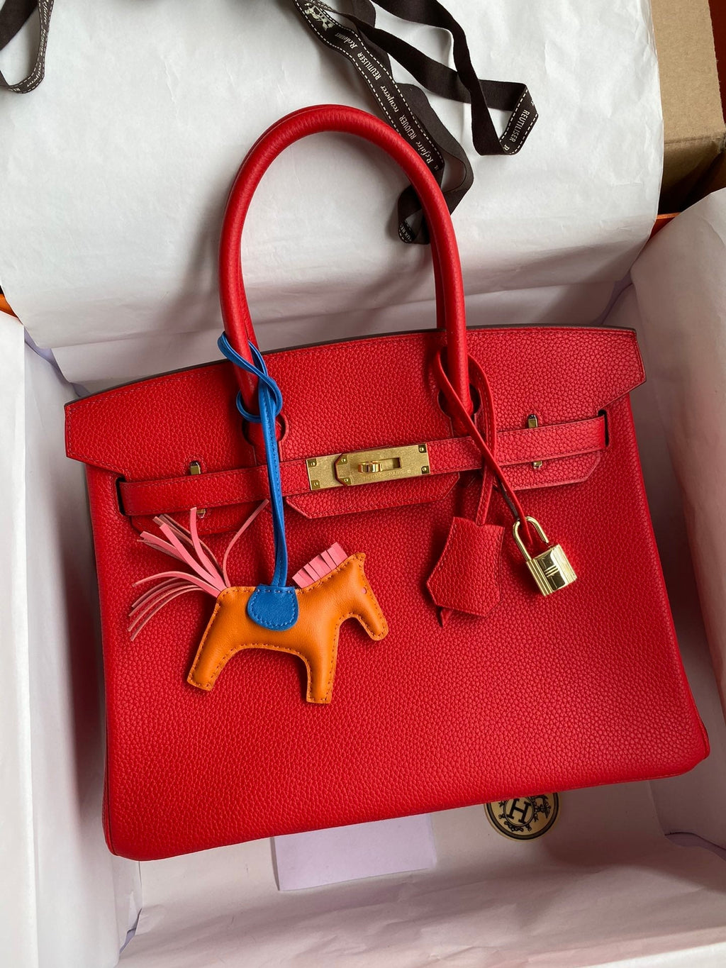Red handbag with colorful charm in a box