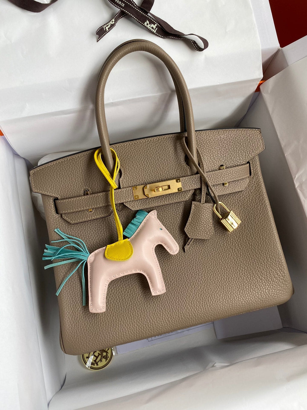 Beige handbag with a horse charm in a white box