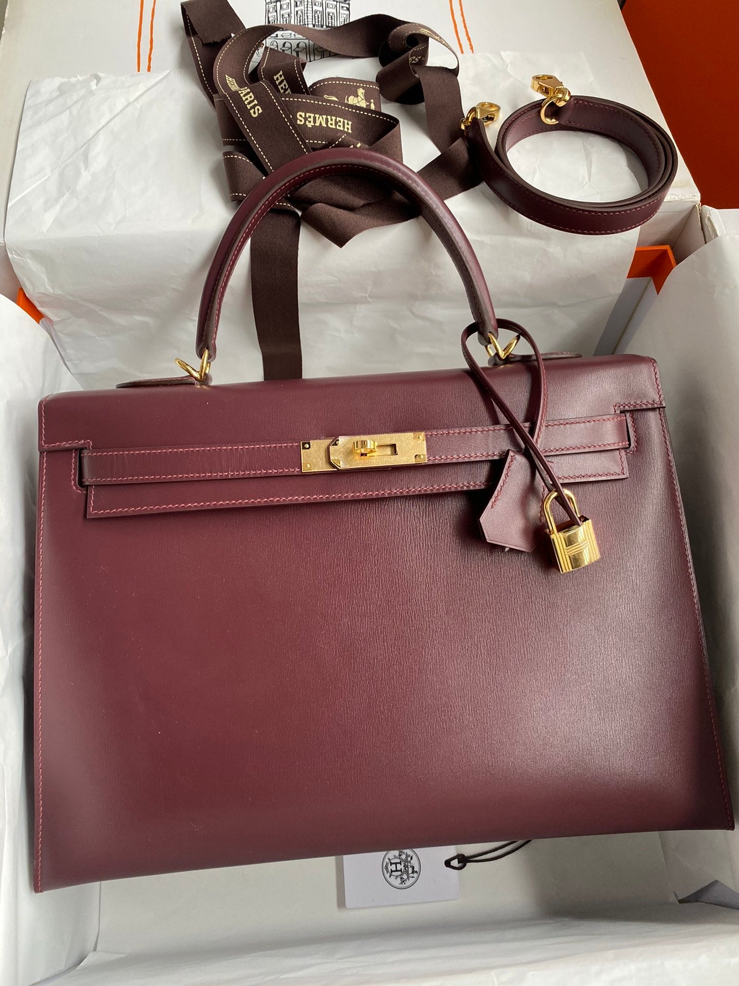 Maroon handbag with gold hardware on a white background