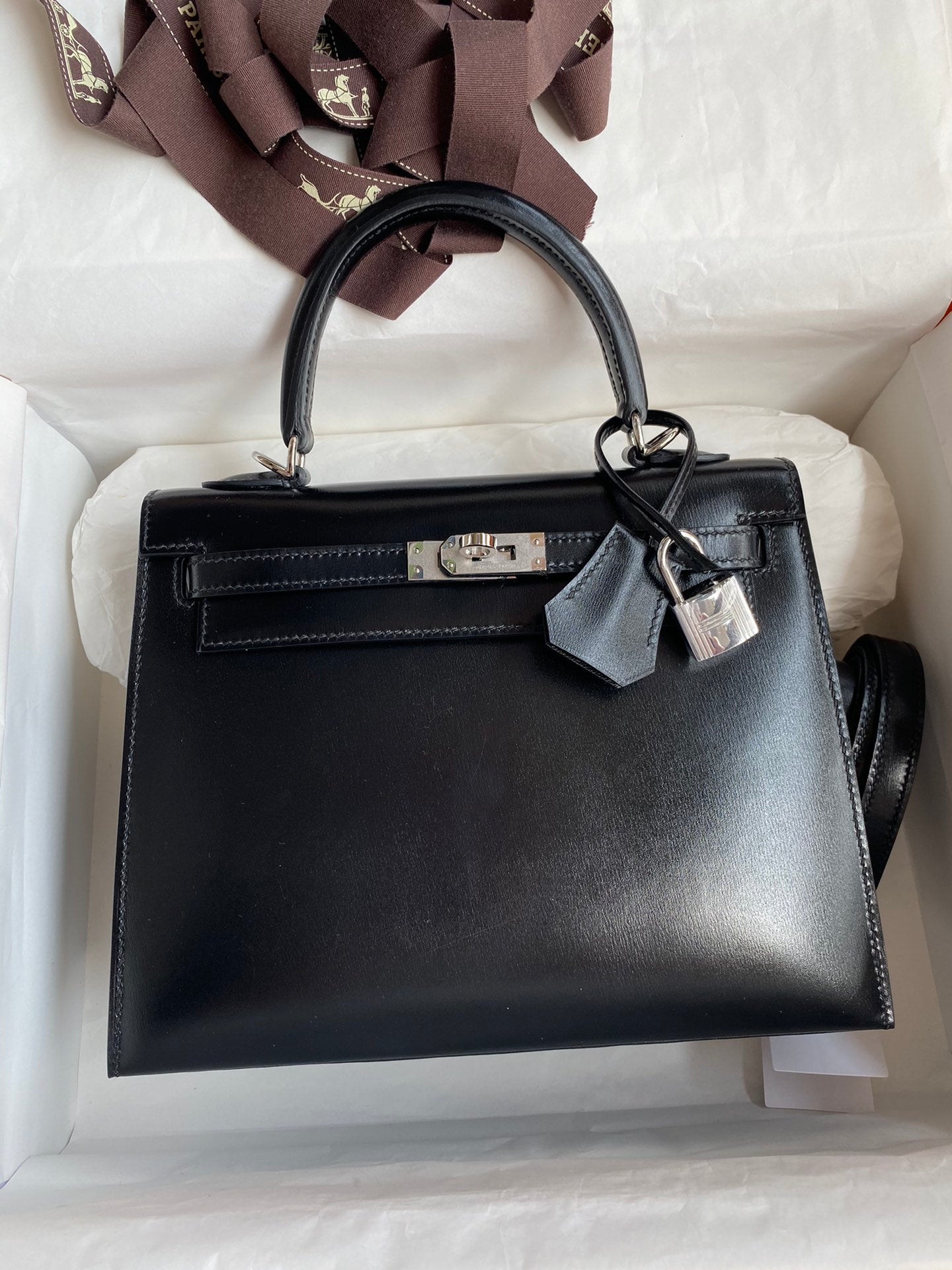 Black handbag with a silver lock on a white cushion