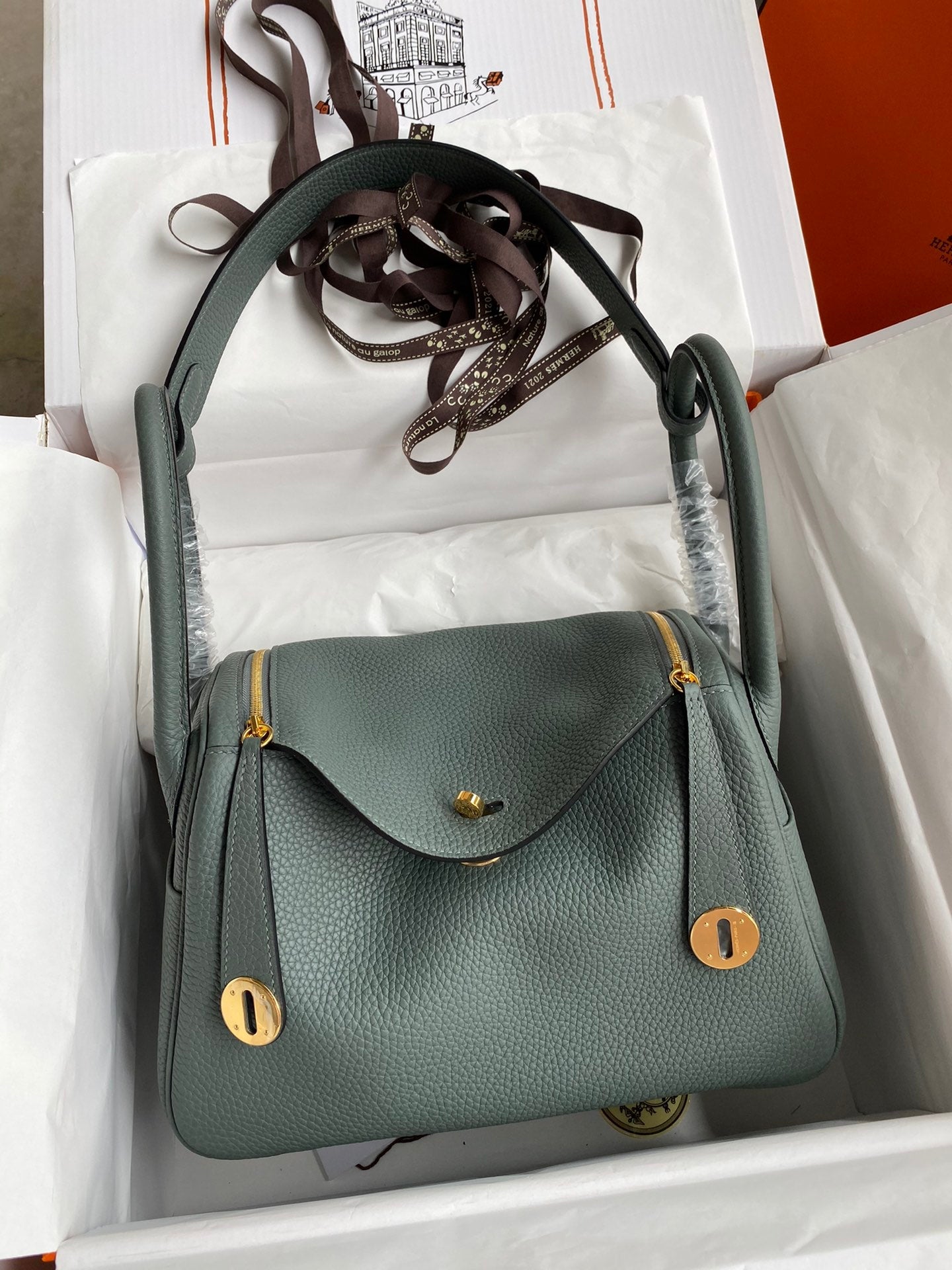 Green handbag with gold accents in a white box