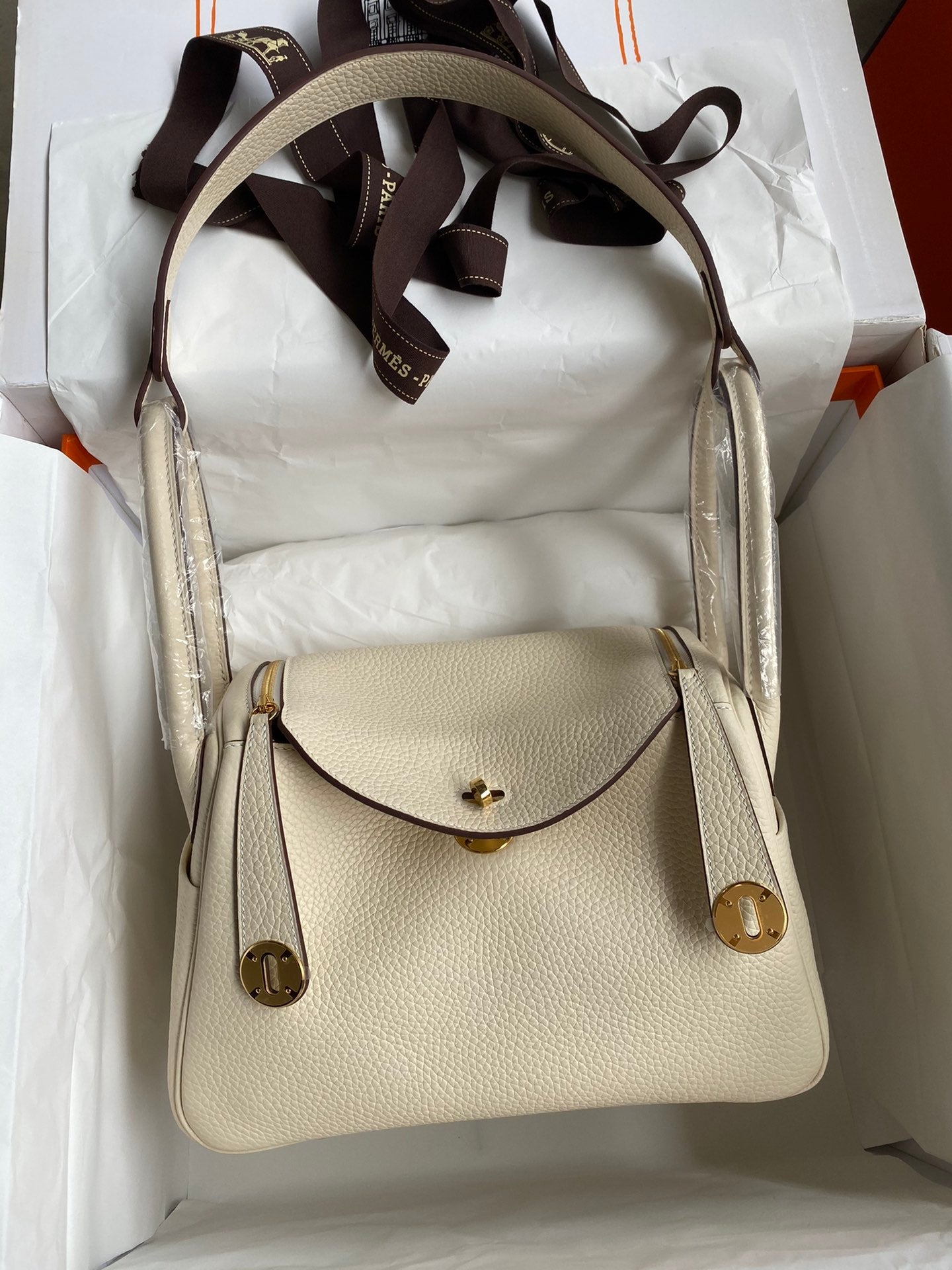 Beige handbag with brown strap in a white box