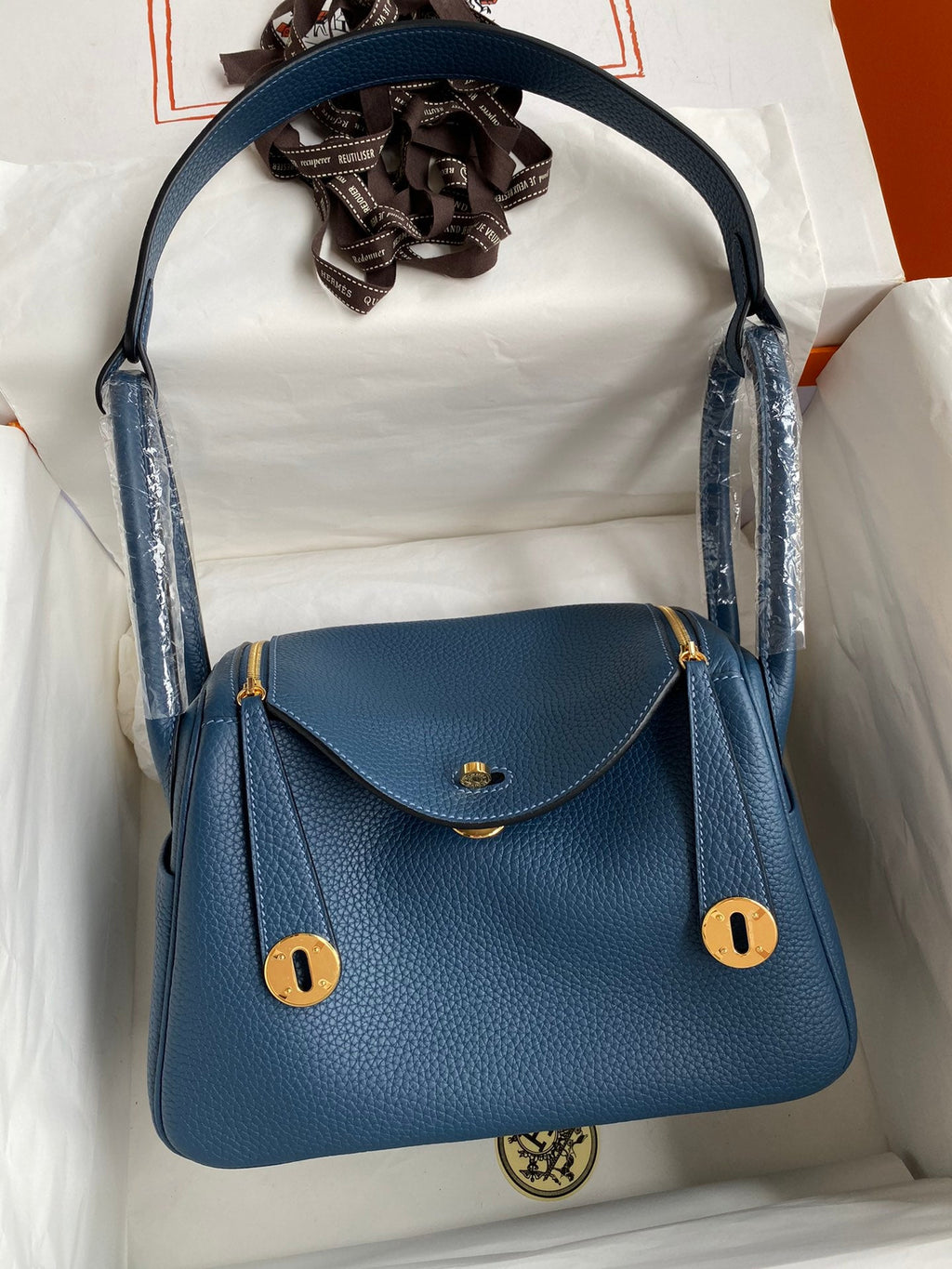 Blue handbag with gold accents on a white background