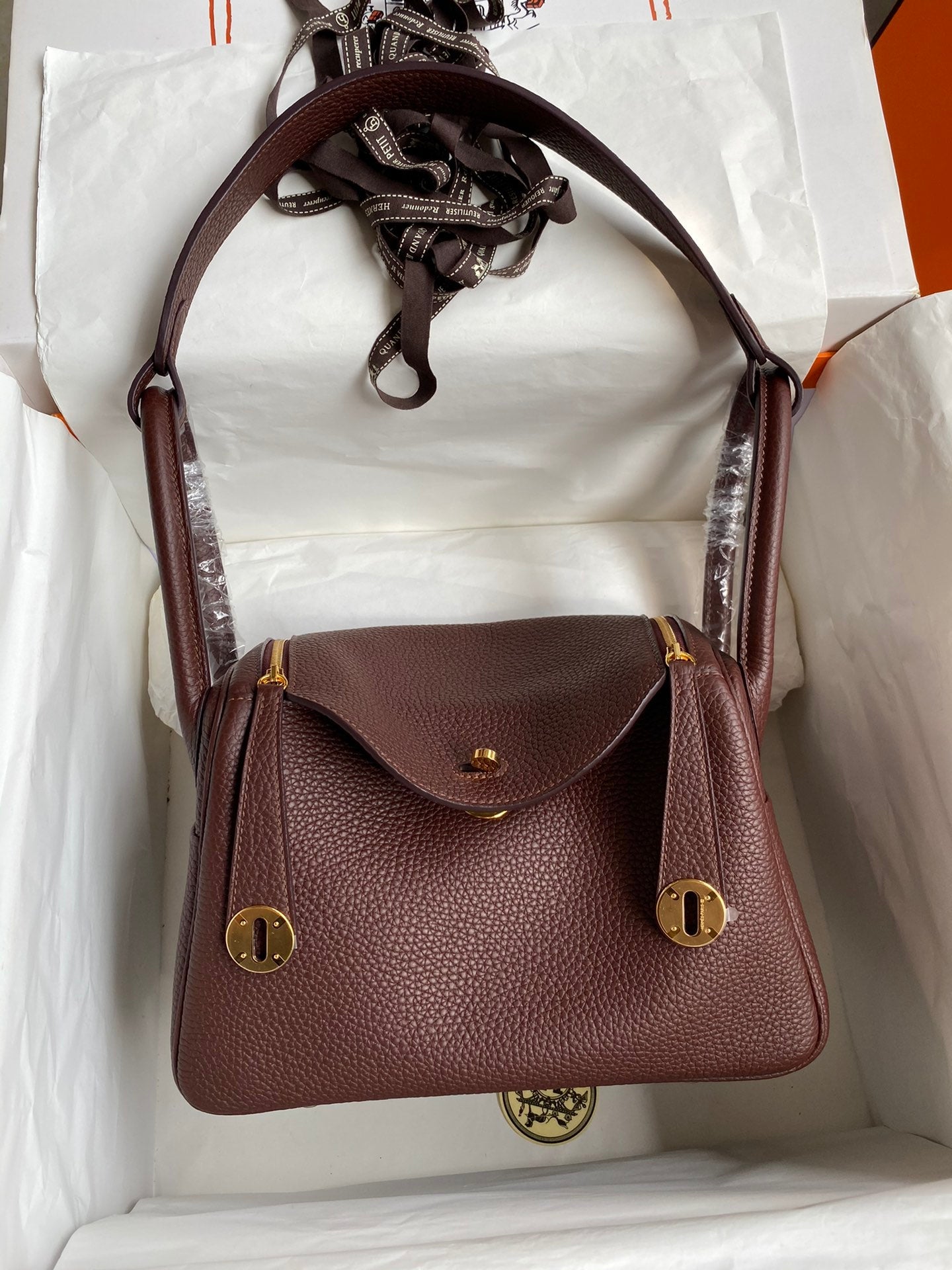 Brown handbag with gold accents in a white box