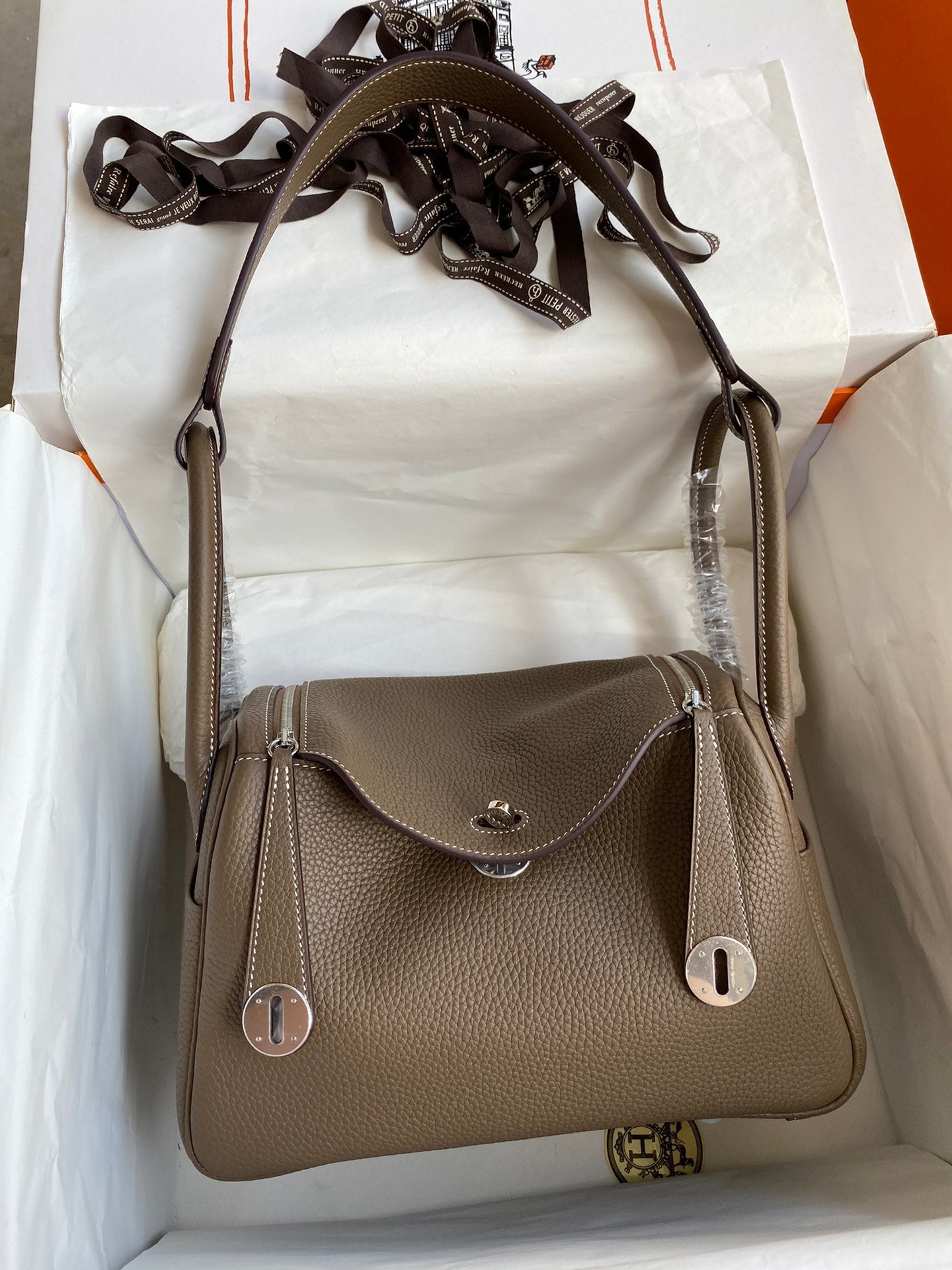 Brown leather handbag with a strap on a white surface
