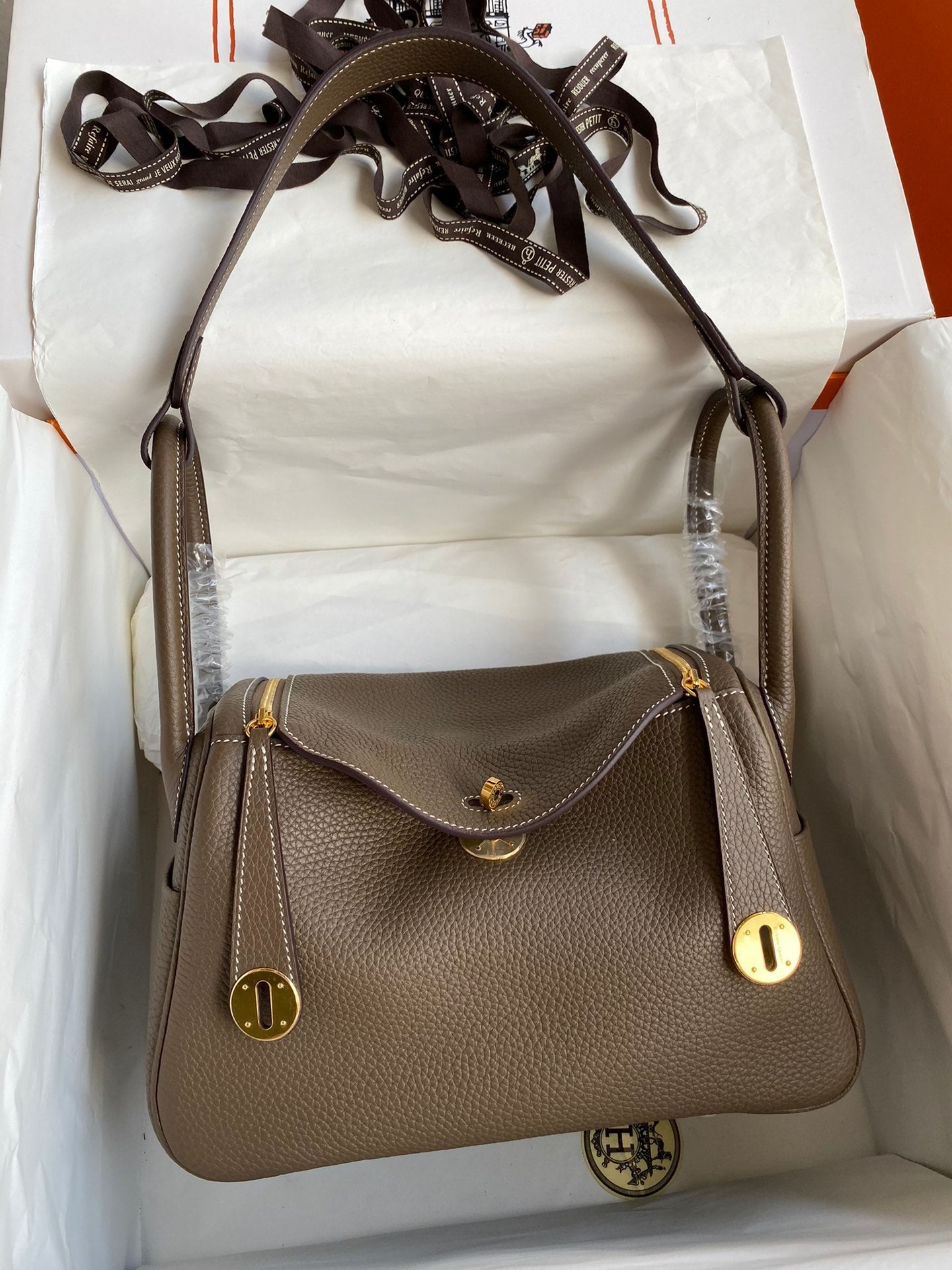 Brown leather handbag with gold accents on a white background