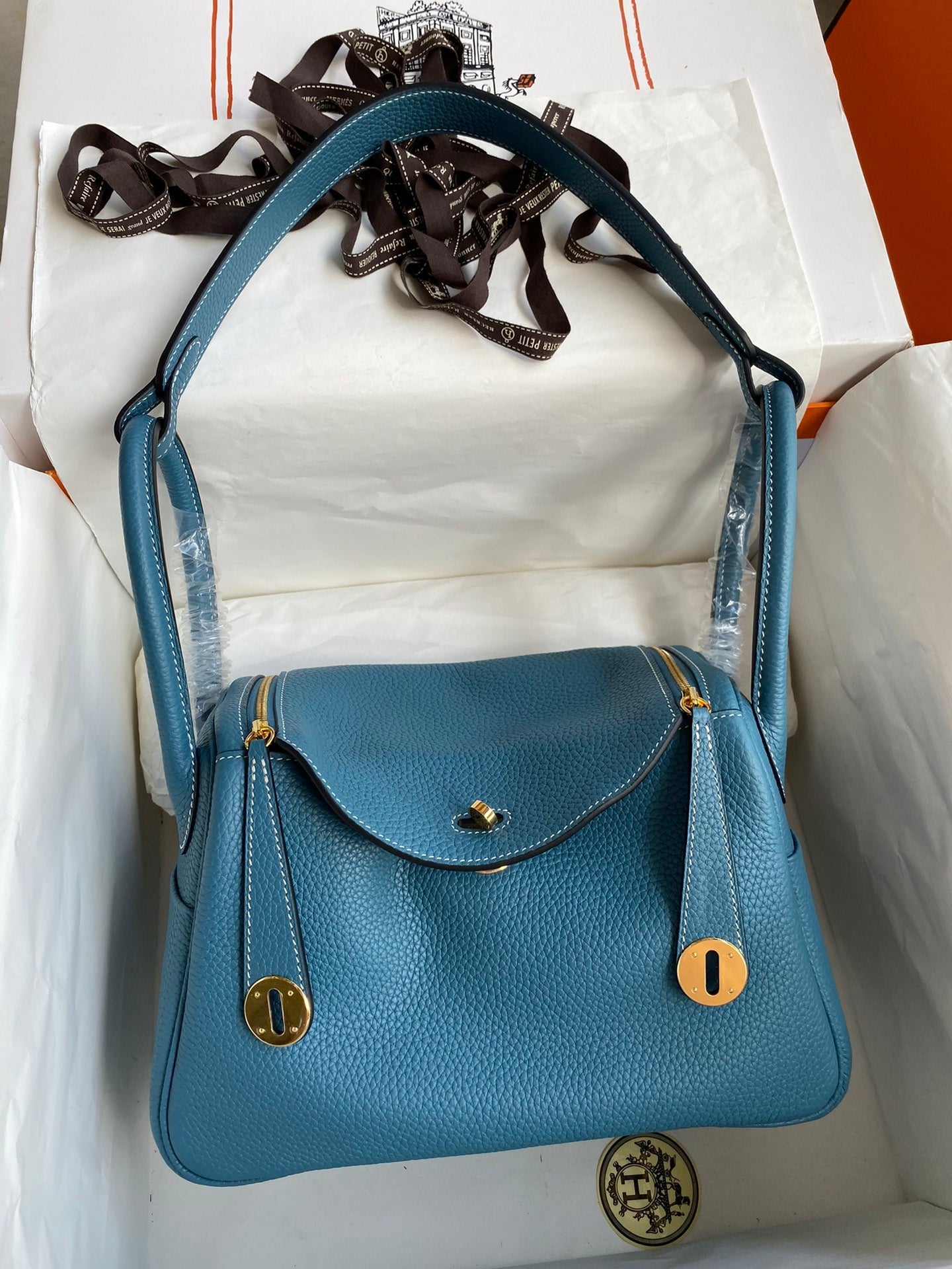 Blue handbag with gold accents on a white surface