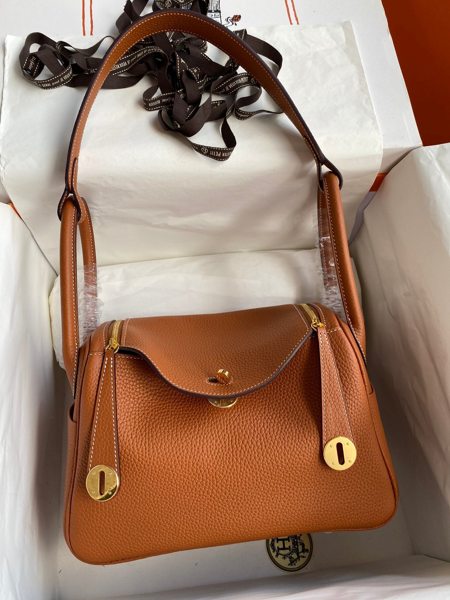 Brown leather handbag with gold accents on a white background