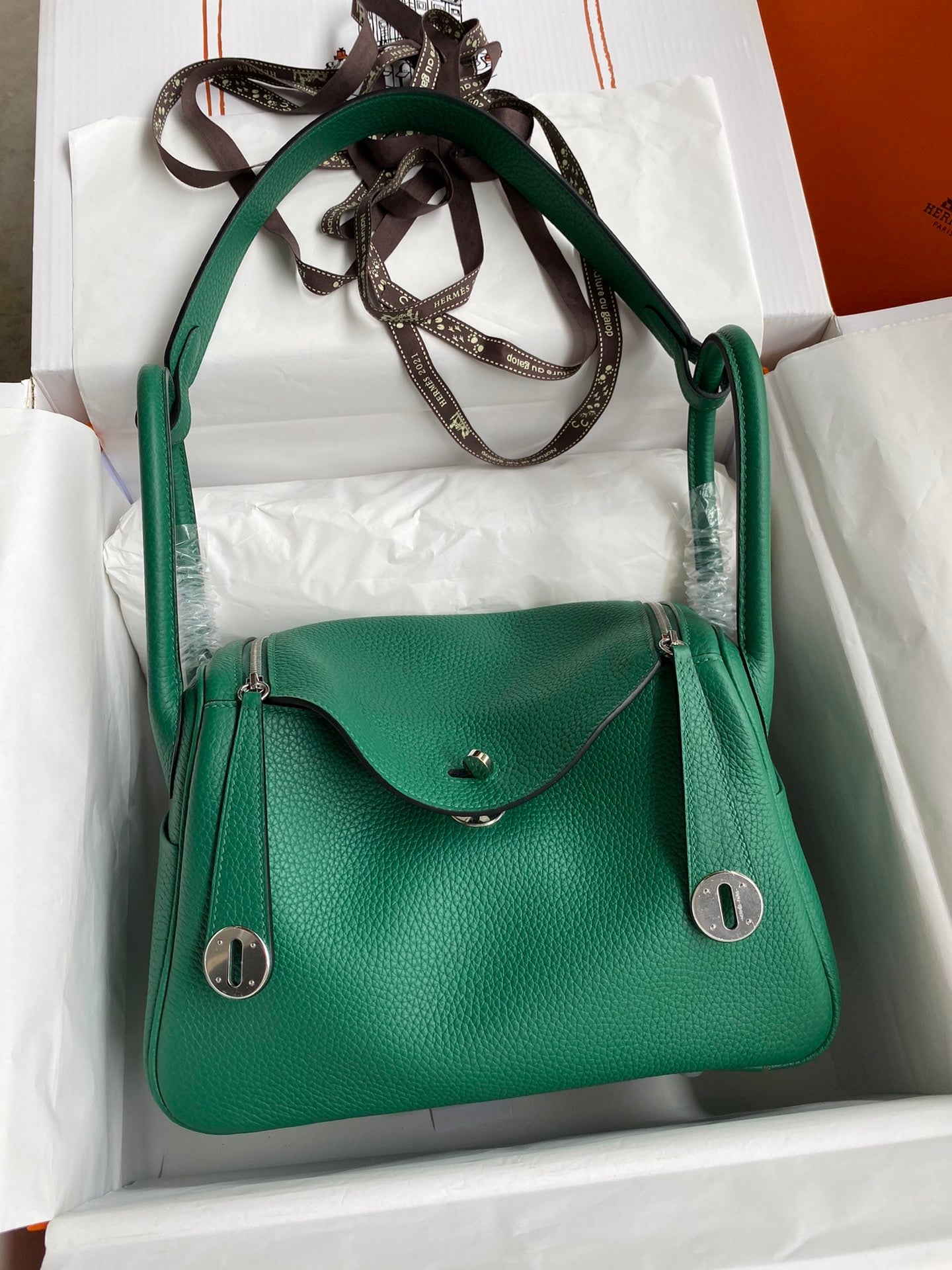 Green handbag with silver hardware in a white box