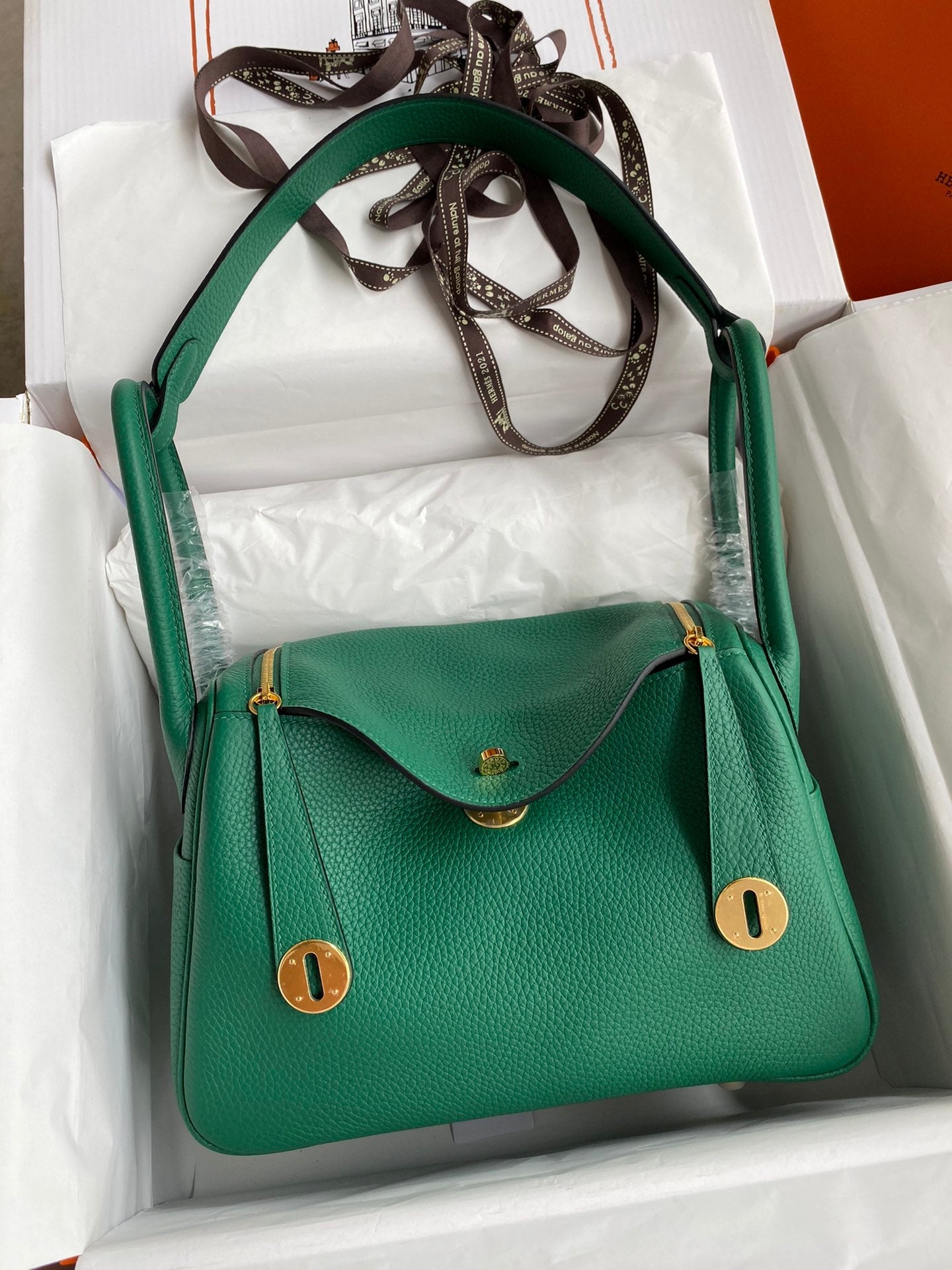 Green handbag with gold accents in a box