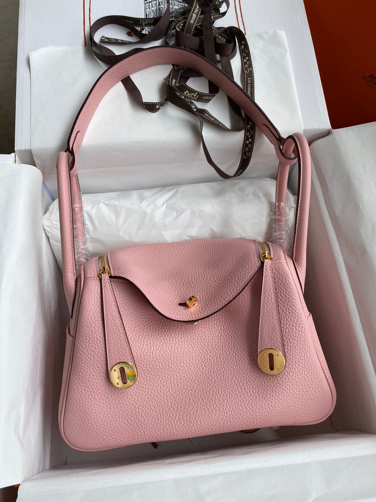 Pink handbag with gold accents in a white box