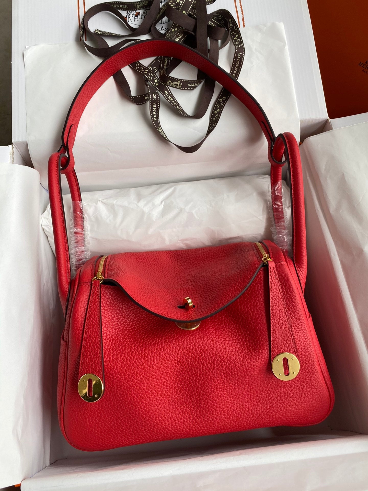 Red handbag with gold accents in a white box