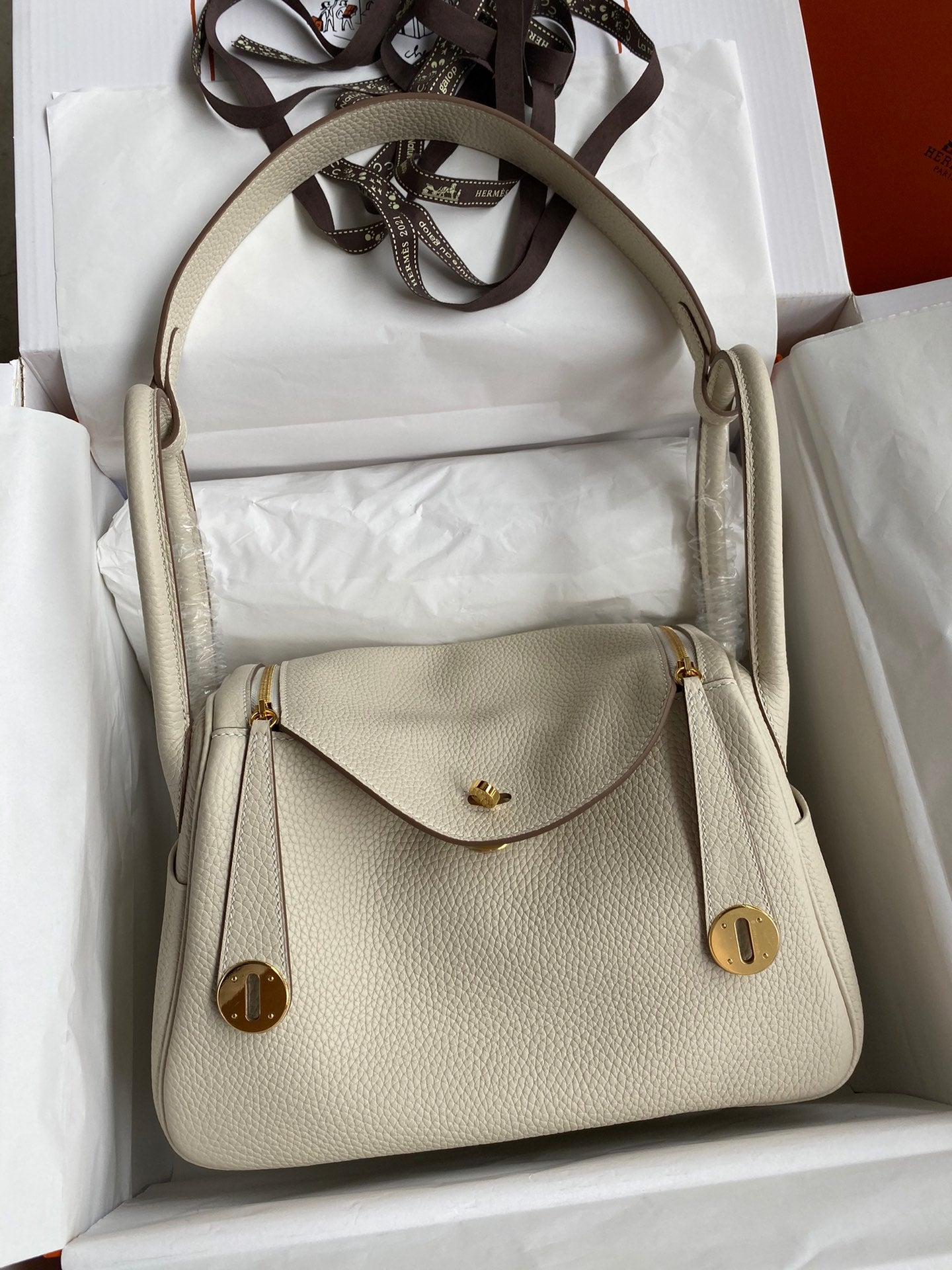 Beige handbag with gold accents in a white box